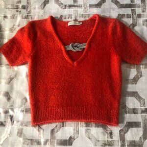 Orange blouse with brooch embellishment.